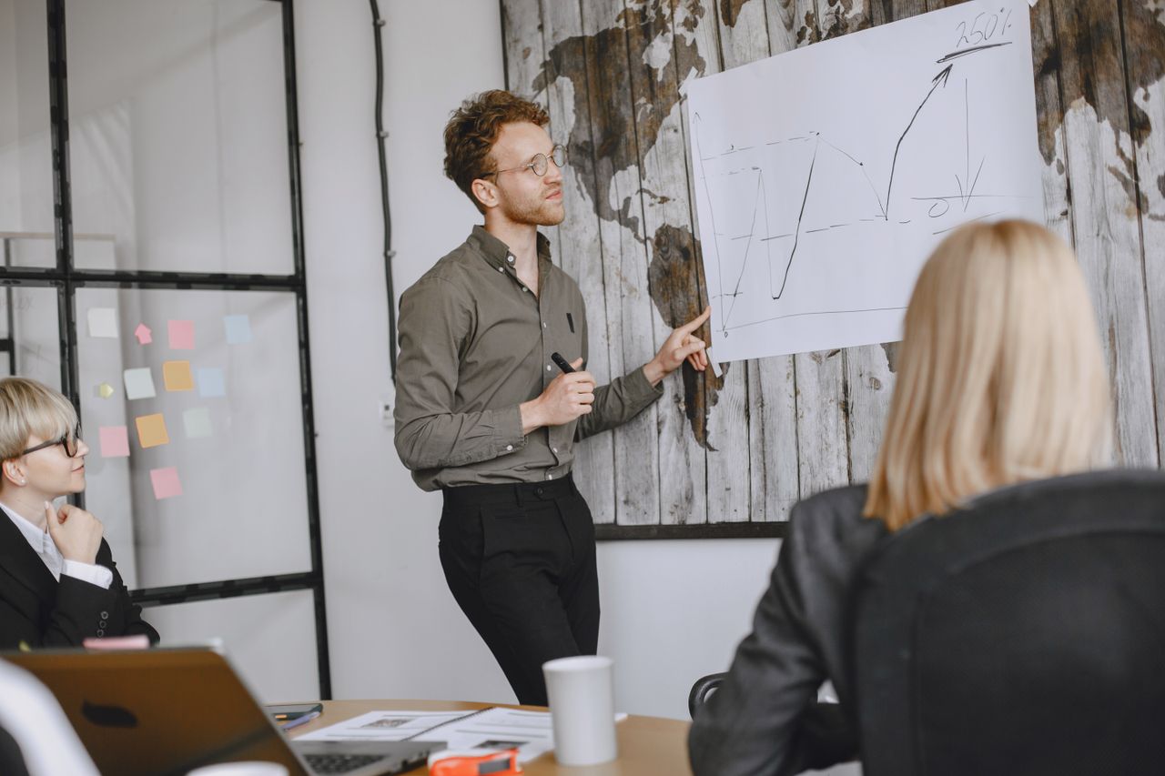 who-we-are A group of professionals engaged in a business meeting with a presentation in a modern office.