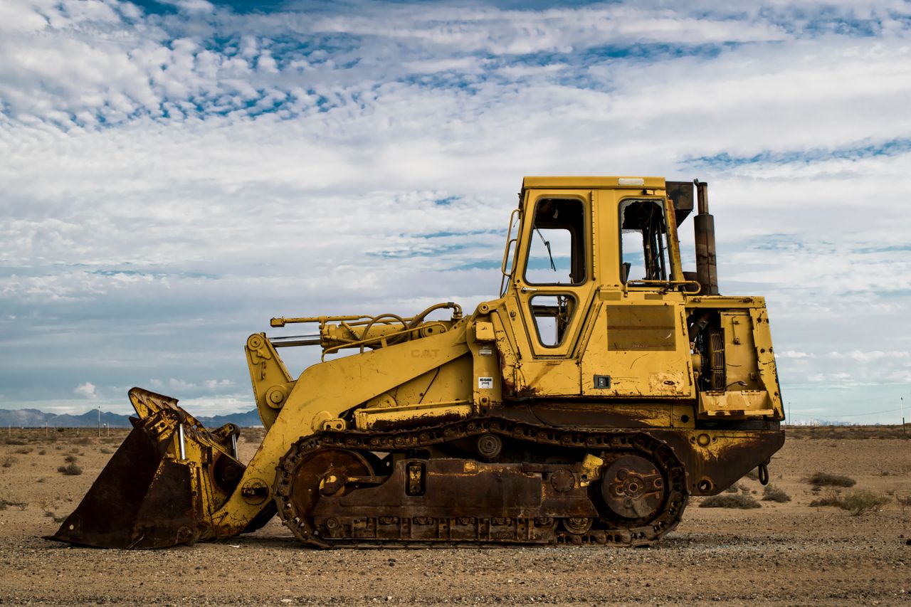 The Art of Drawing Readers In: Your attractive post title goes here Abandoned rusty bulldozer parked in a serene desert landscape under a cloudy sky.